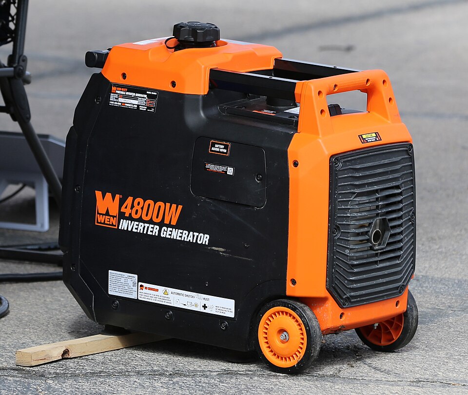 An orange and black WEN 4800 inverter generator with wheels, sitting on pavement, for storm prep in Daphne, AL